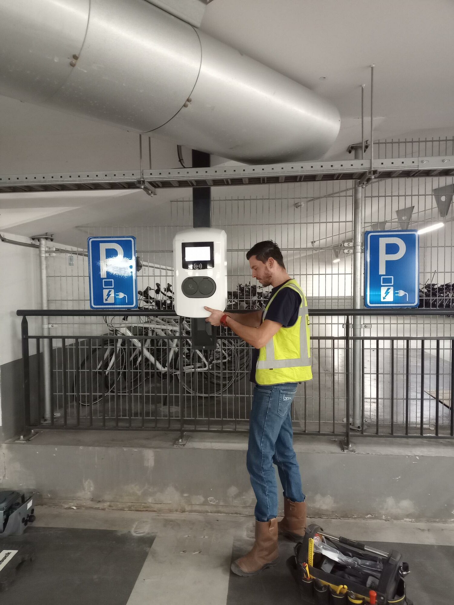 Monteur installeert een laadpaal in een ondergrondse parkeergarage